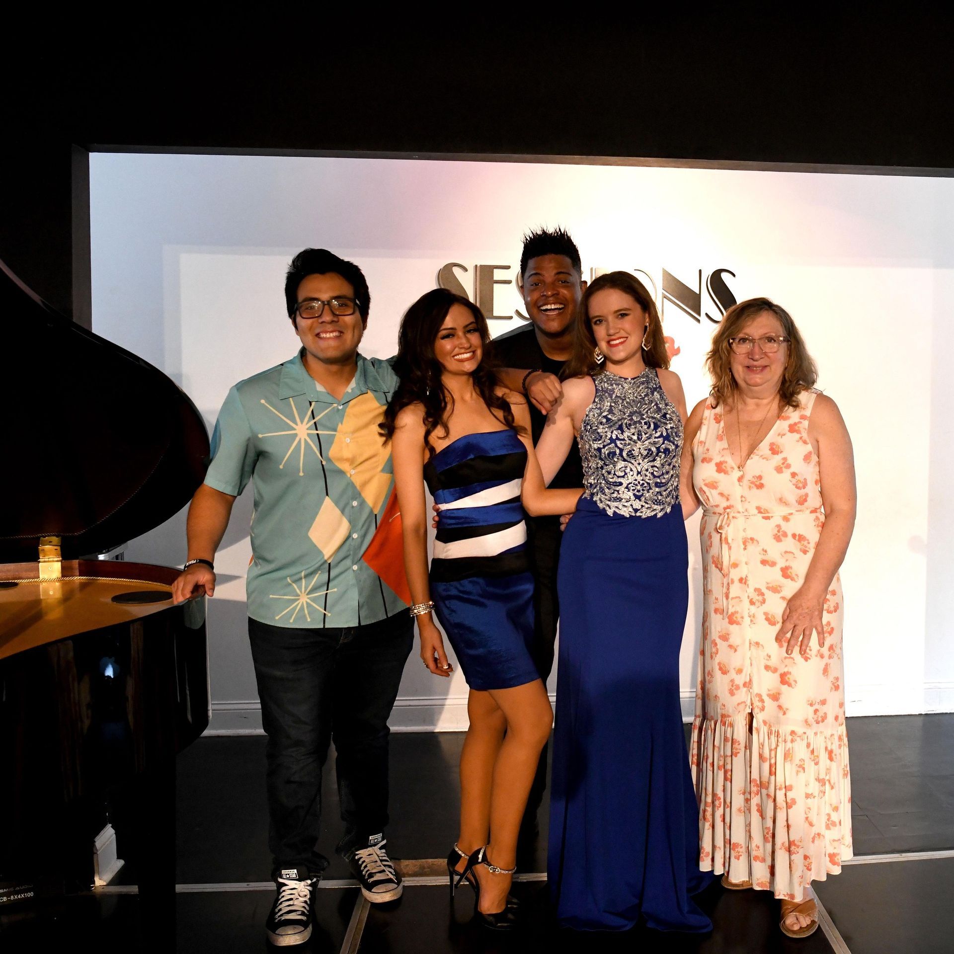 A group of people posing for a picture in front of a piano