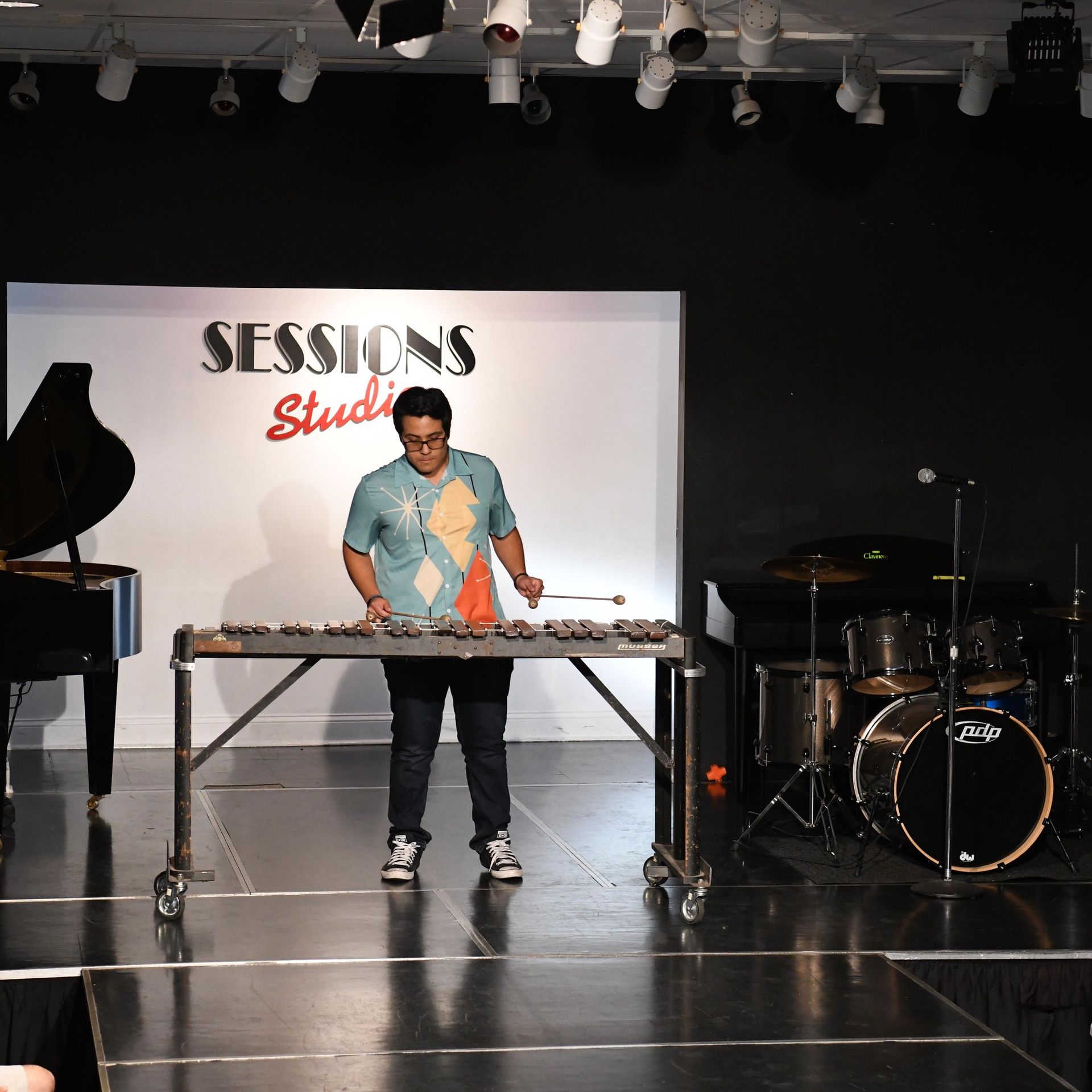 A man stands in front of a sign that says sessions studio