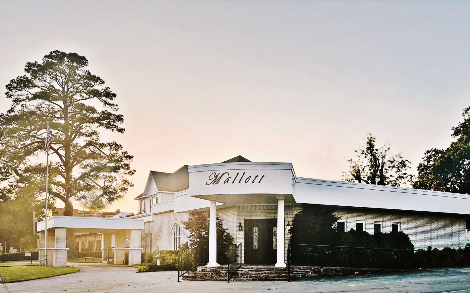 The front door of a house with a porch and plants in front of it.