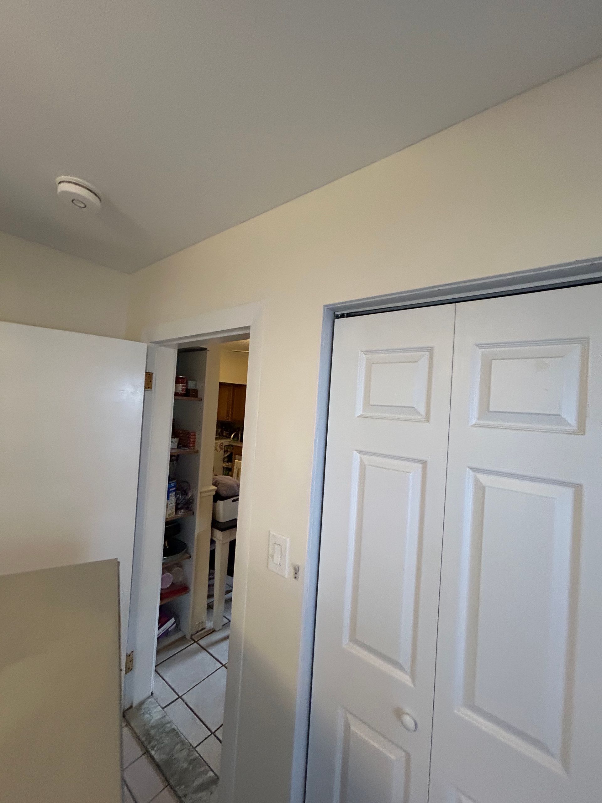 A white door is open to a kitchen in a house.