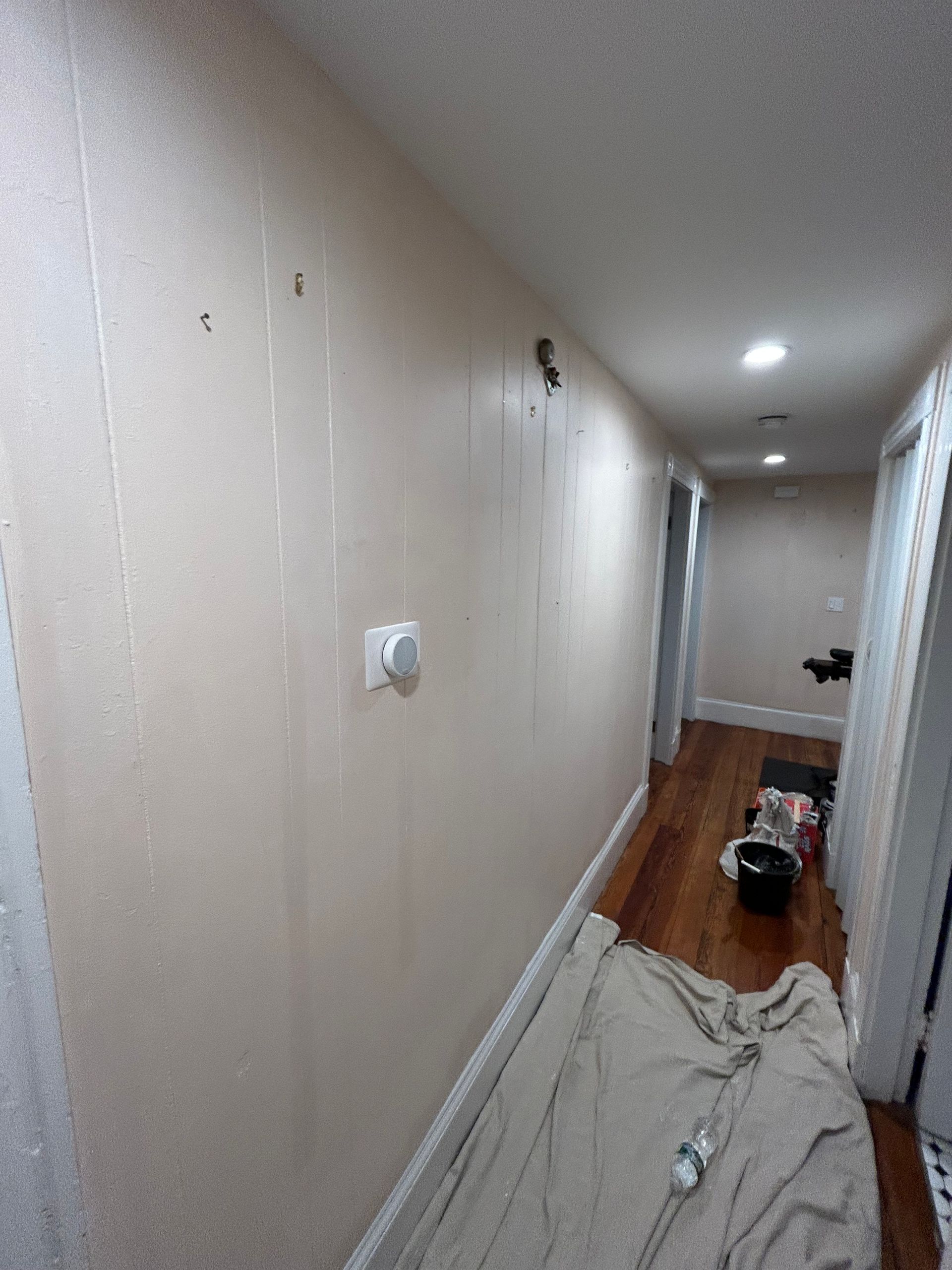 A hallway with a blanket on the floor and a bucket on the floor.