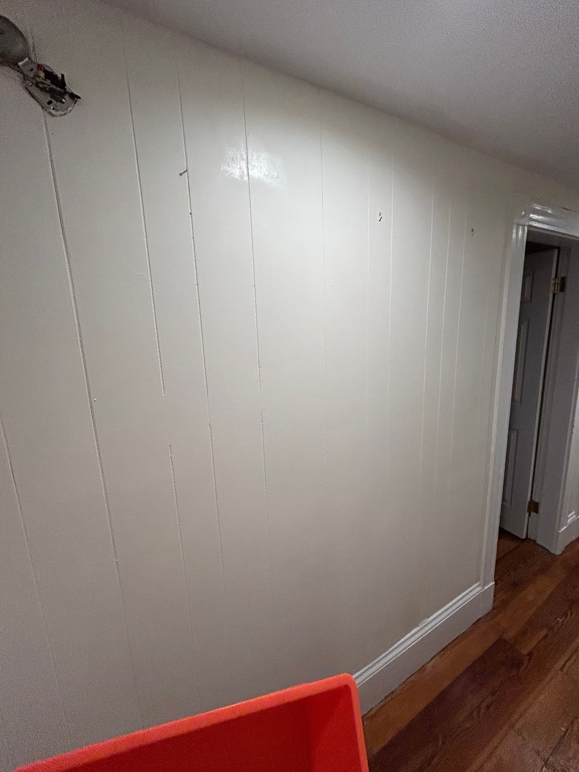 A room with a white wall and a wooden floor.