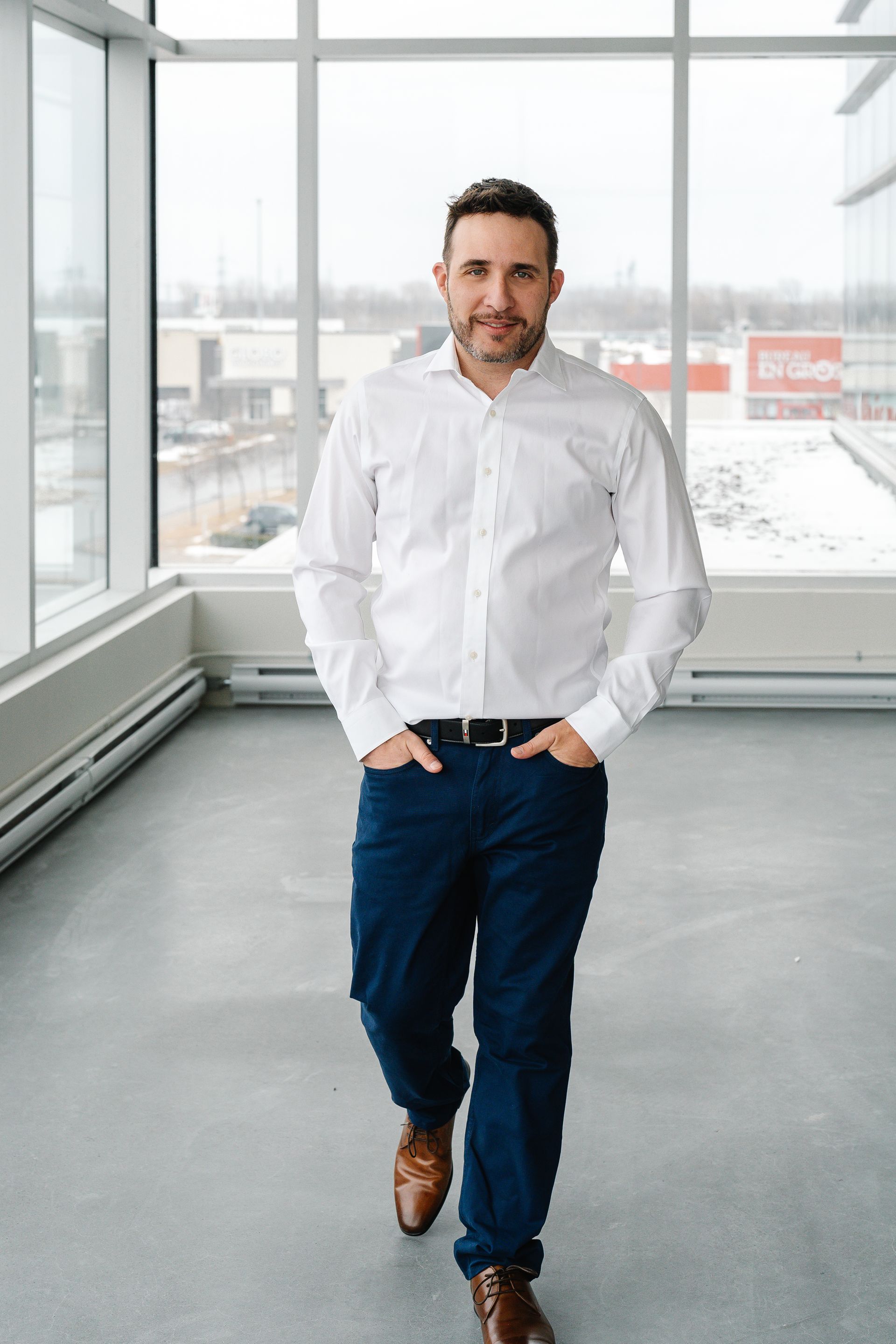 Un homme en chemise blanche et pantalon bleu marche dans un couloir.