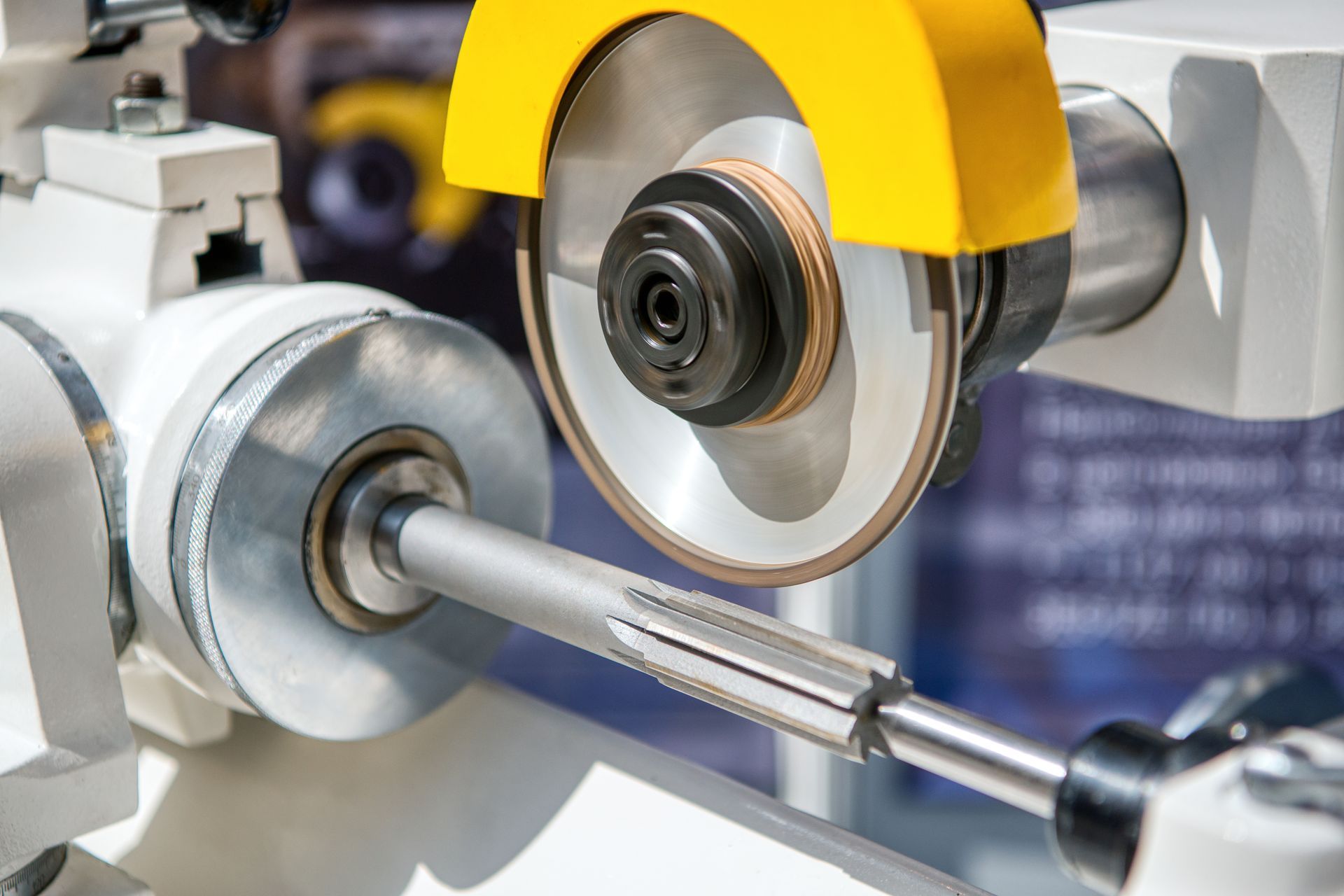 Close-up of equipment spline cutting process on steel shaft using precision grinding tool.