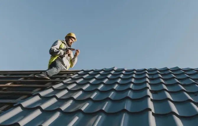 A man is standing on top of a tiled roof.