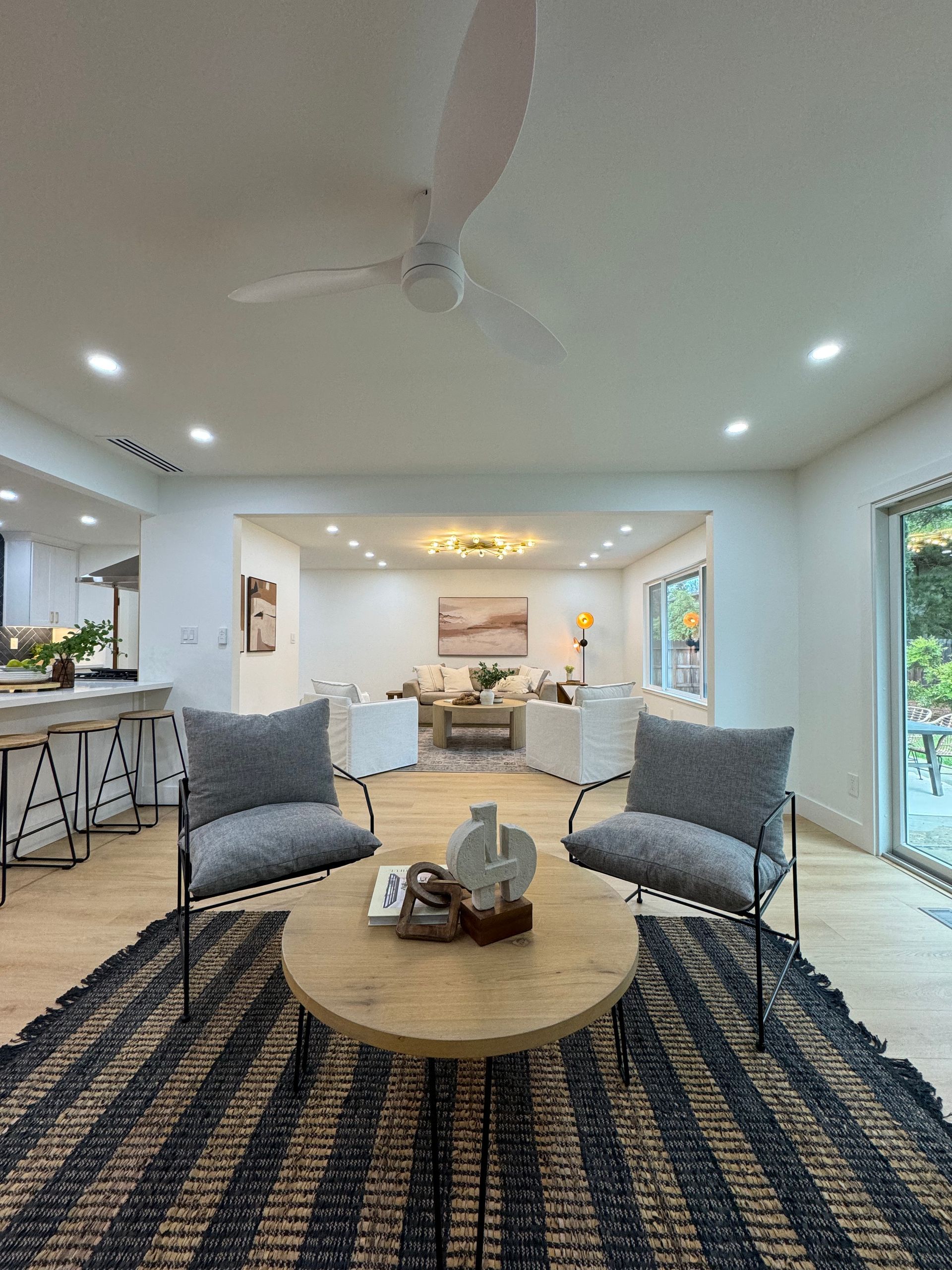 A living room with a round table and chairs and a ceiling fan.