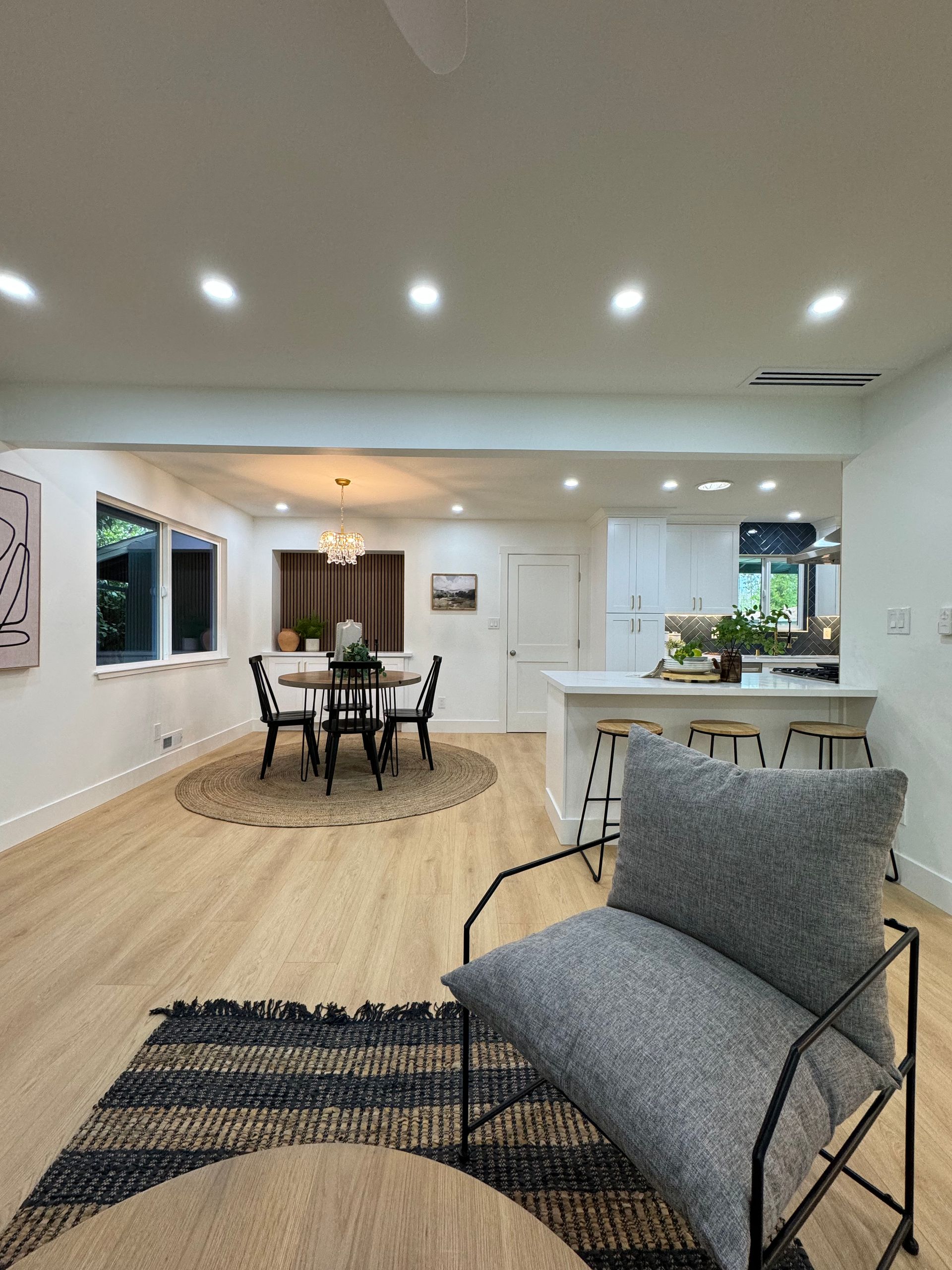 A living room with a chair , rug , table and chairs.