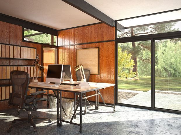 A home office with a desk , chair , computer and large windows.