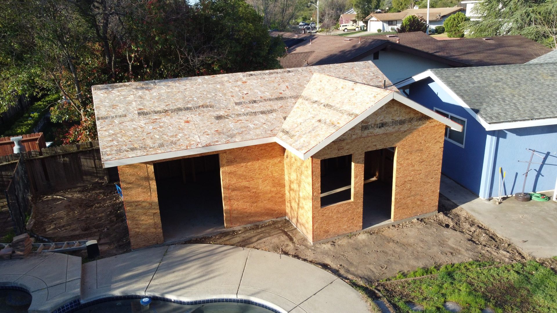 An aerial view of a house under construction with a pool in the backyard