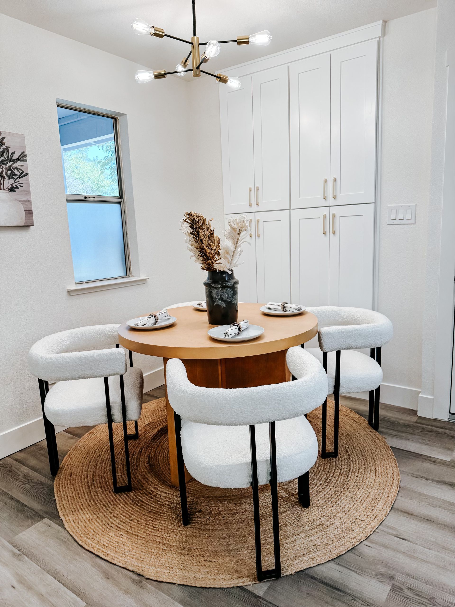 A dining room with a round table and white chairs