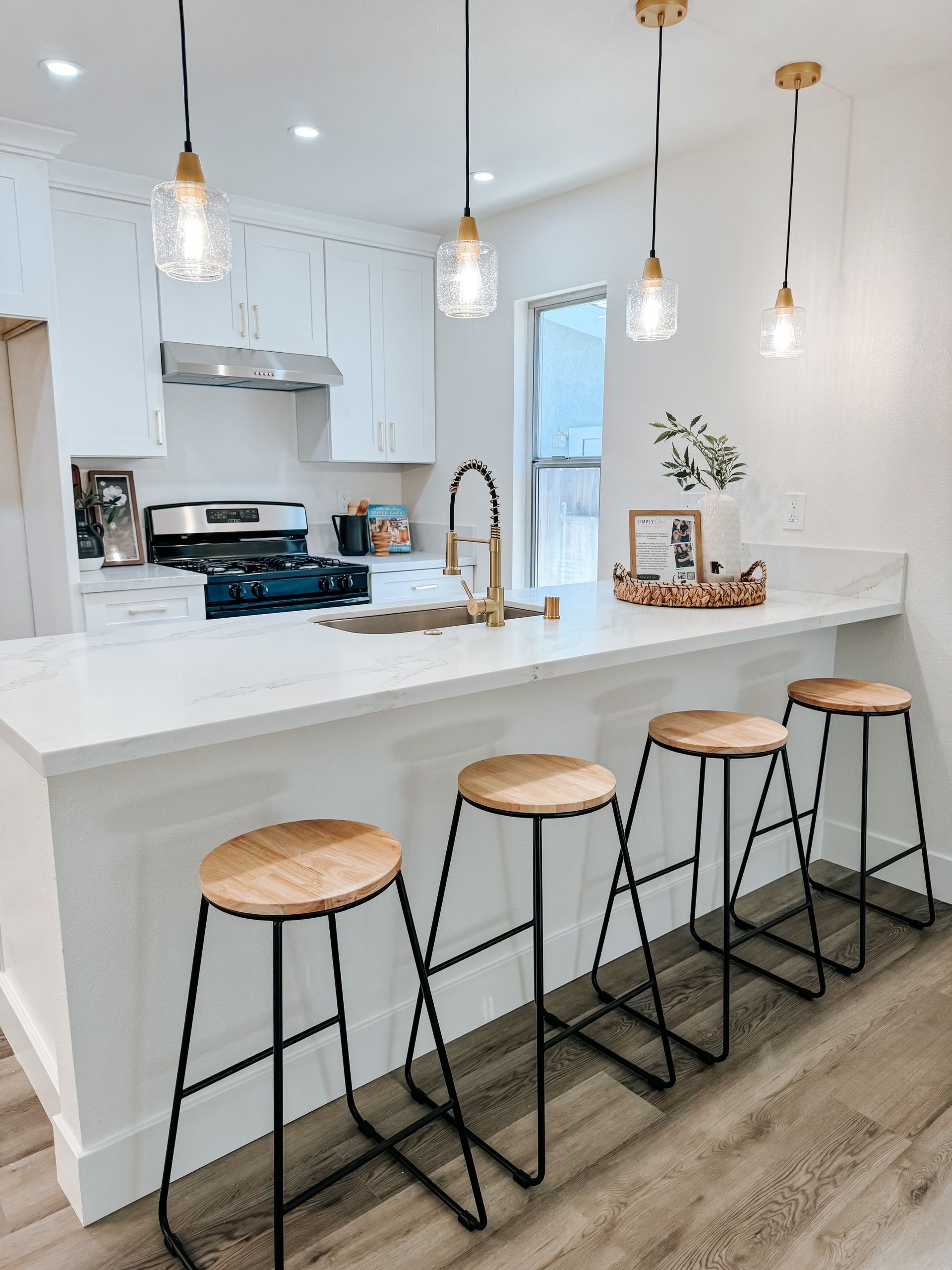 A kitchen with a long island , stools , a sink and a stove.