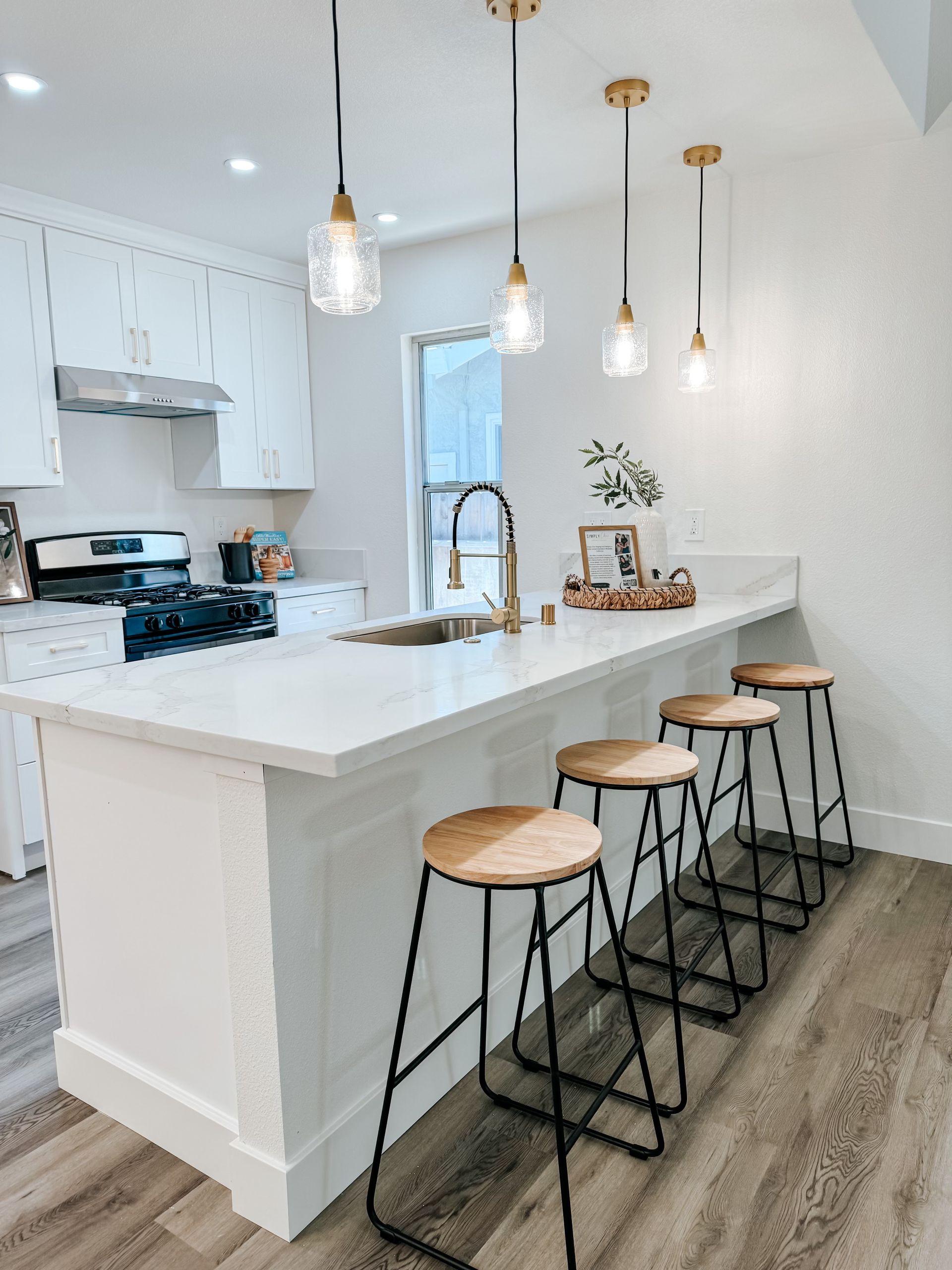 A kitchen with a long island , stools , a sink and a stove.