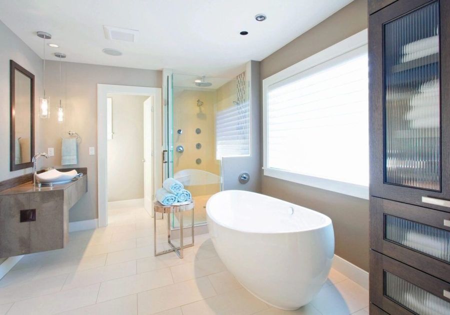 A bathroom with a tub , sink , mirror and window.