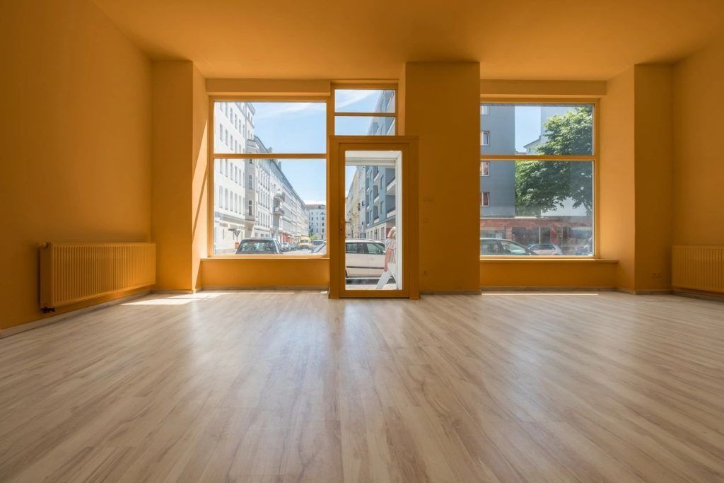 An empty room with hardwood floors and orange walls.