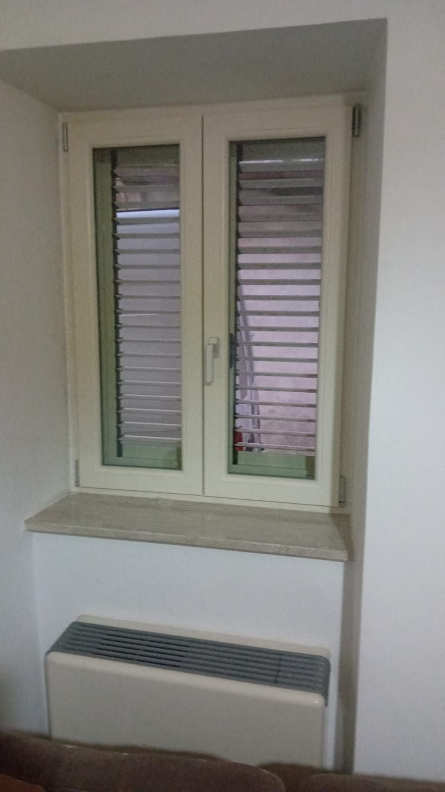 Un soggiorno con una finestra e un termosifone.