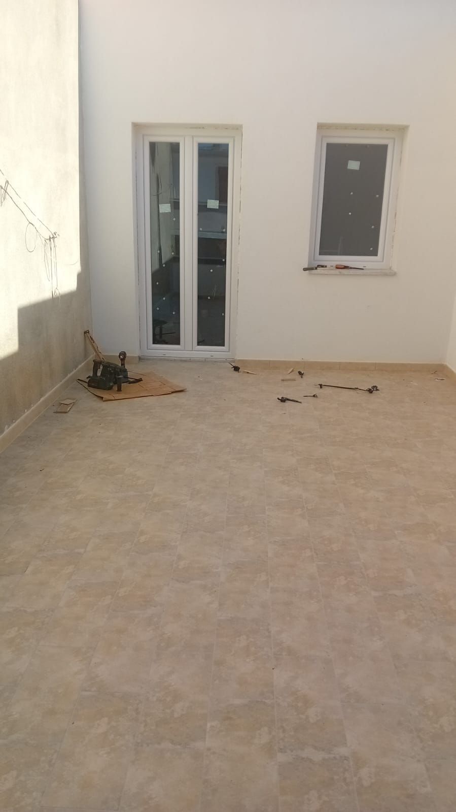 Un patio con una porta scorrevole in vetro e due finestre.