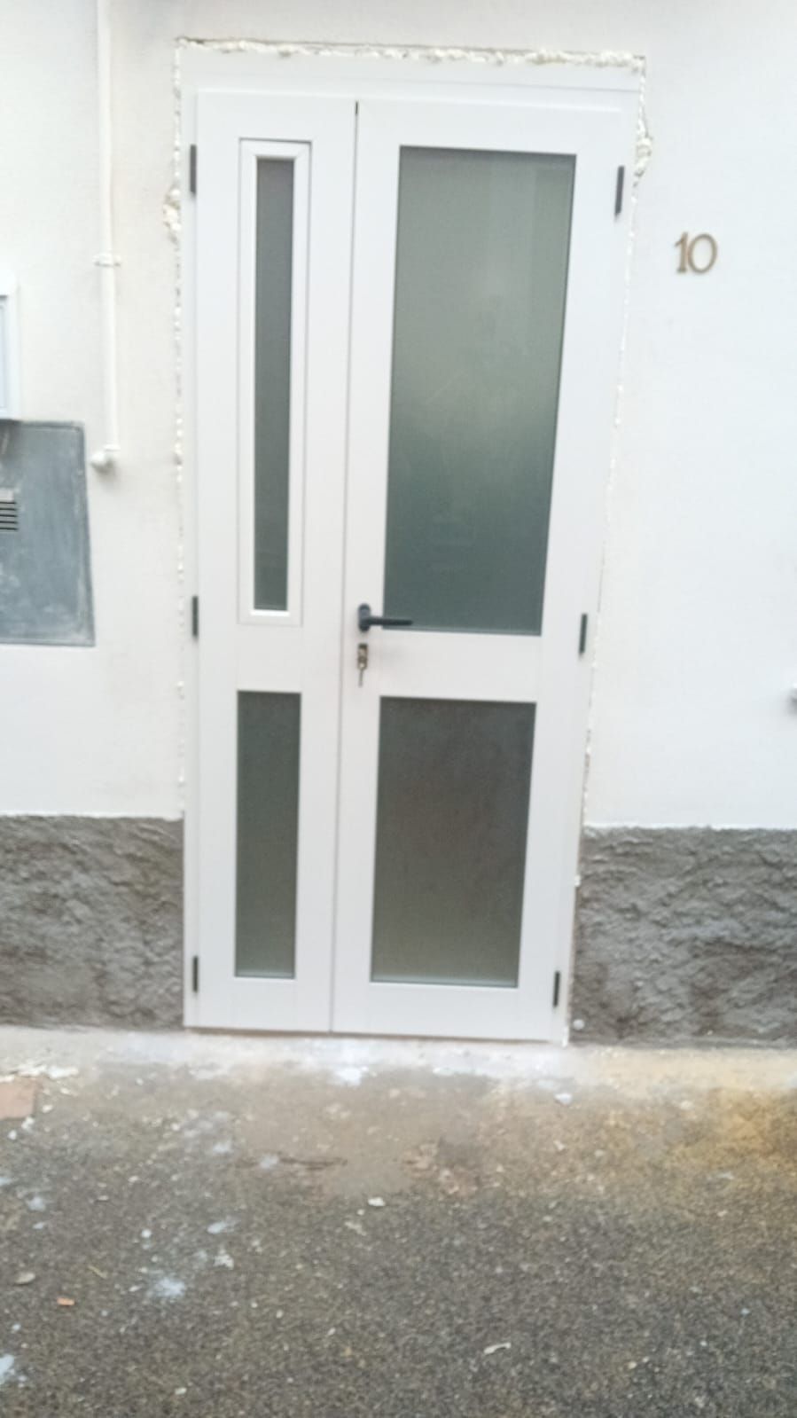 Una porta bianca con vetro smerigliato si trova sul lato di un edificio.