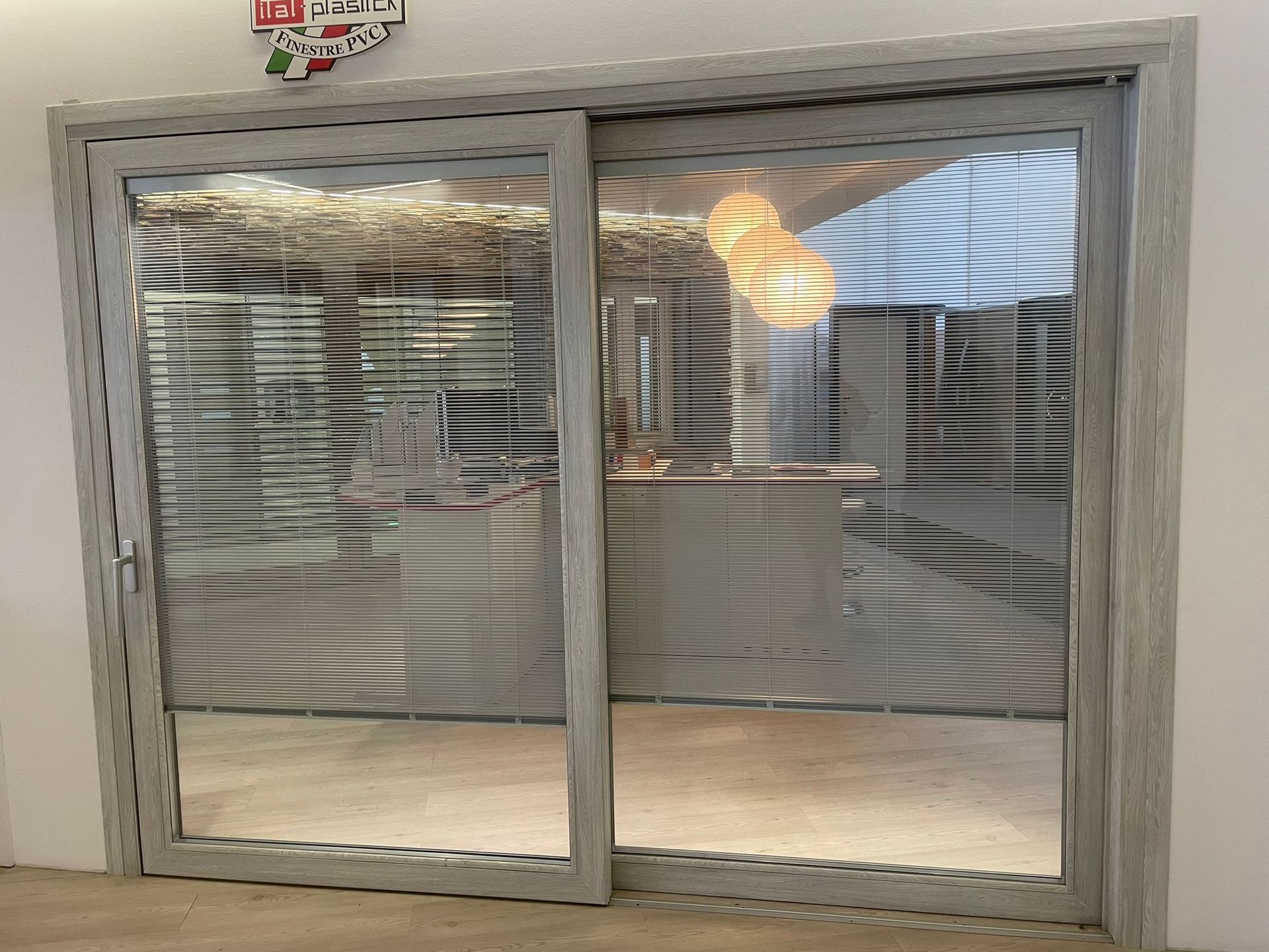 Una porta scorrevole in vetro con le persiane in una stanza.