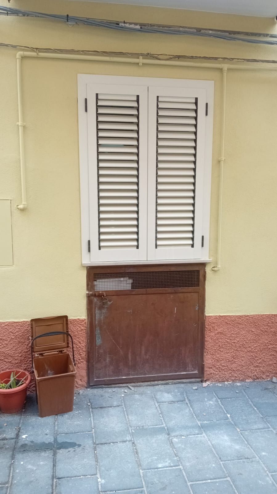 Una finestra con le persiane si trova su un muro giallo.