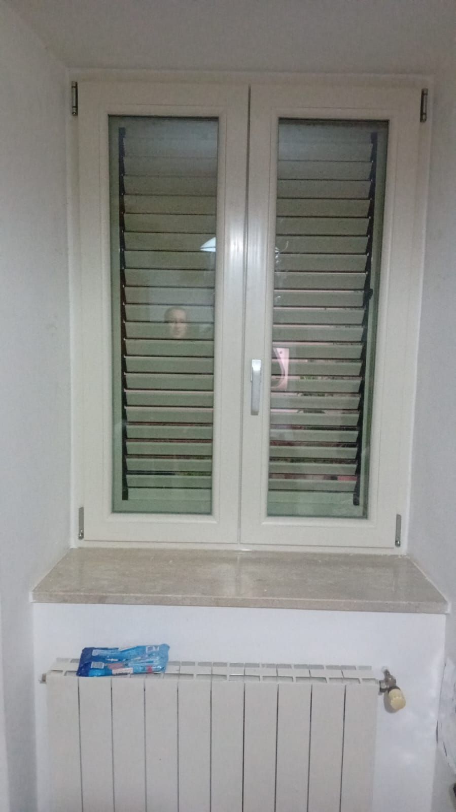 Una finestra con persiane e un termosifone in una stanza.