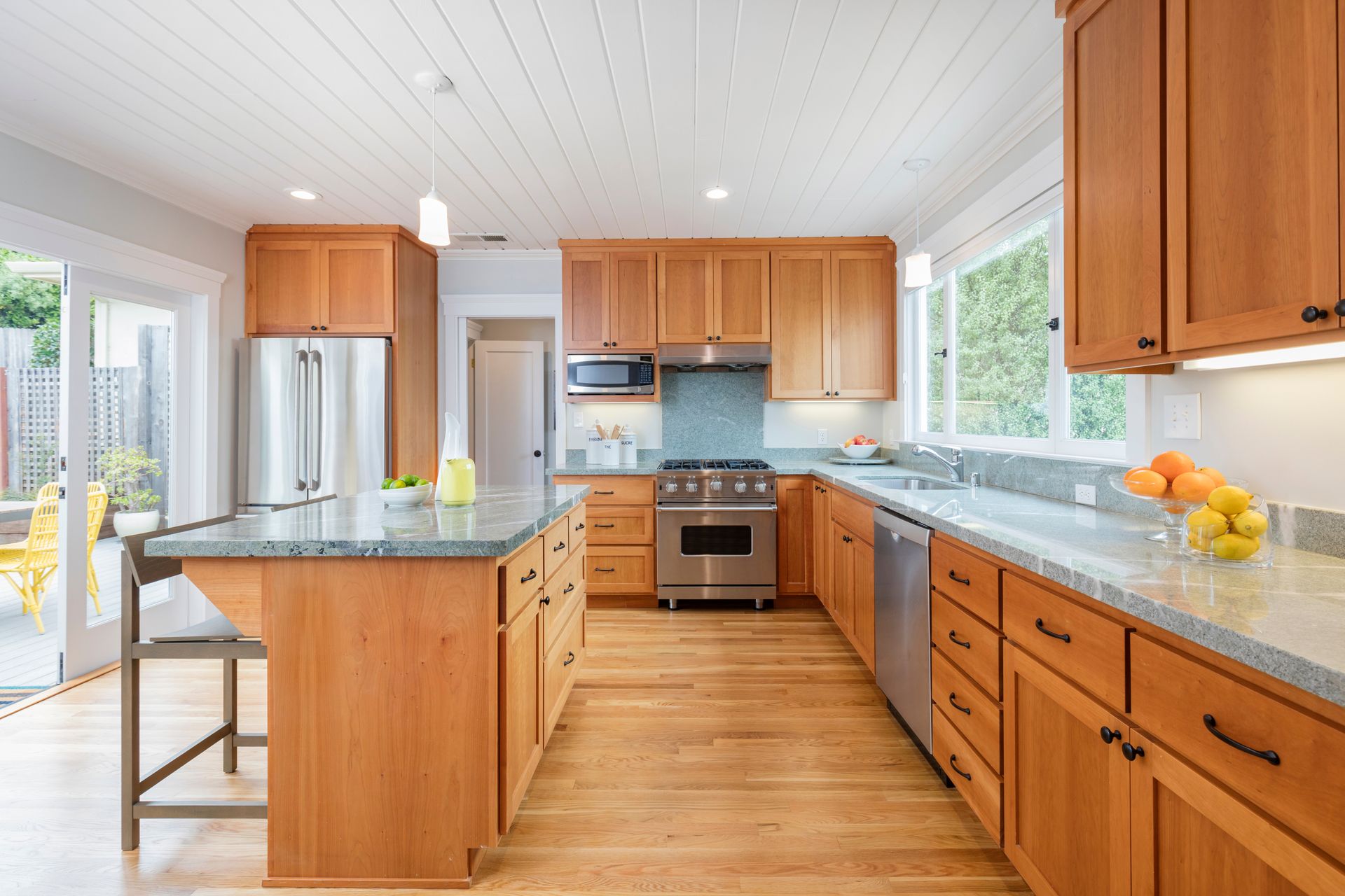 A bright kitchen with light wood cabinets, granite countertops, stainless steel appliances, and wood floors.