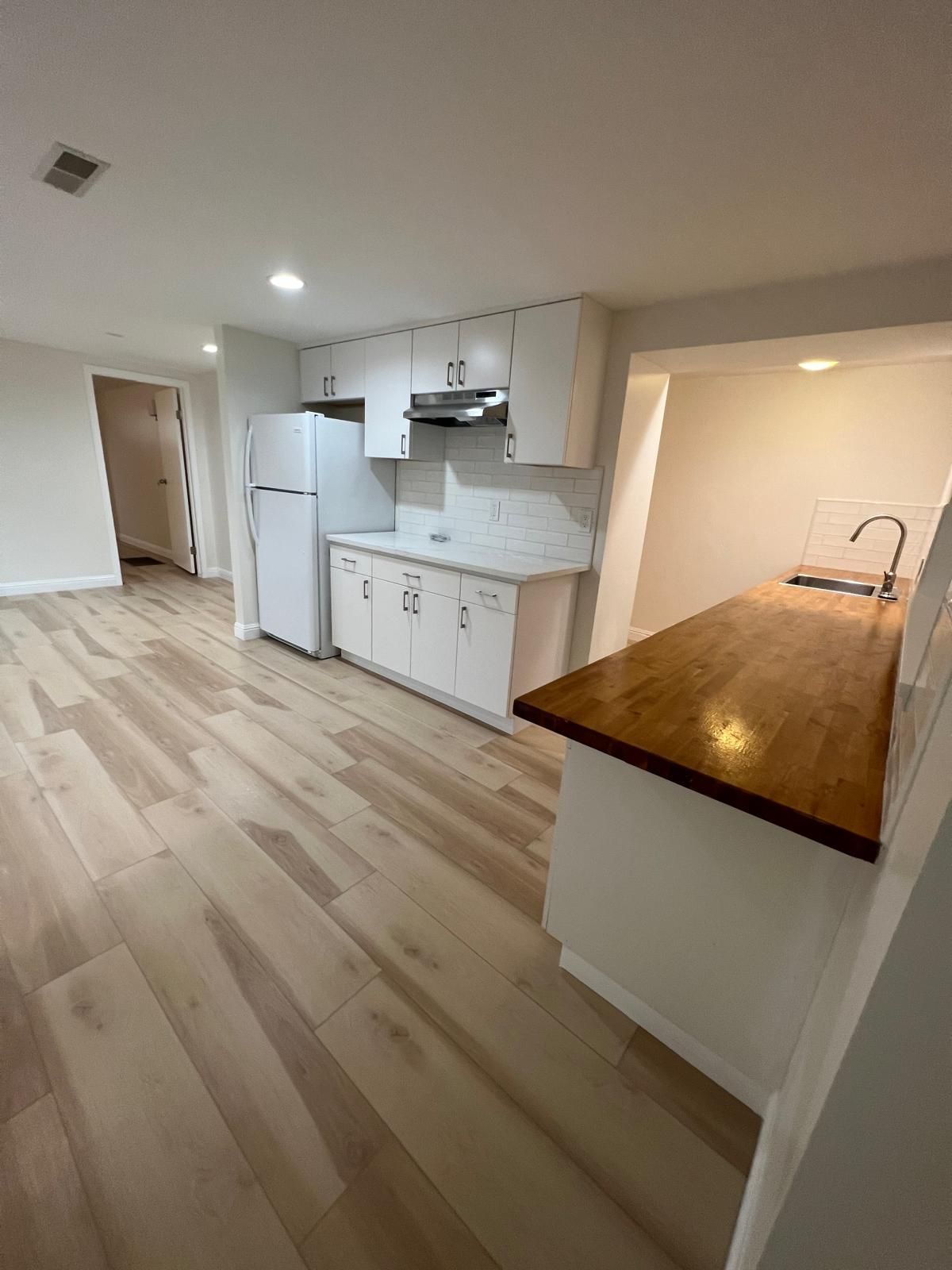 A kitchen undergoing construction, featuring white cabinets, granite countertops, and an exposed wood-framed wall.