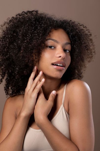 a woman with curly hair is touching her face .