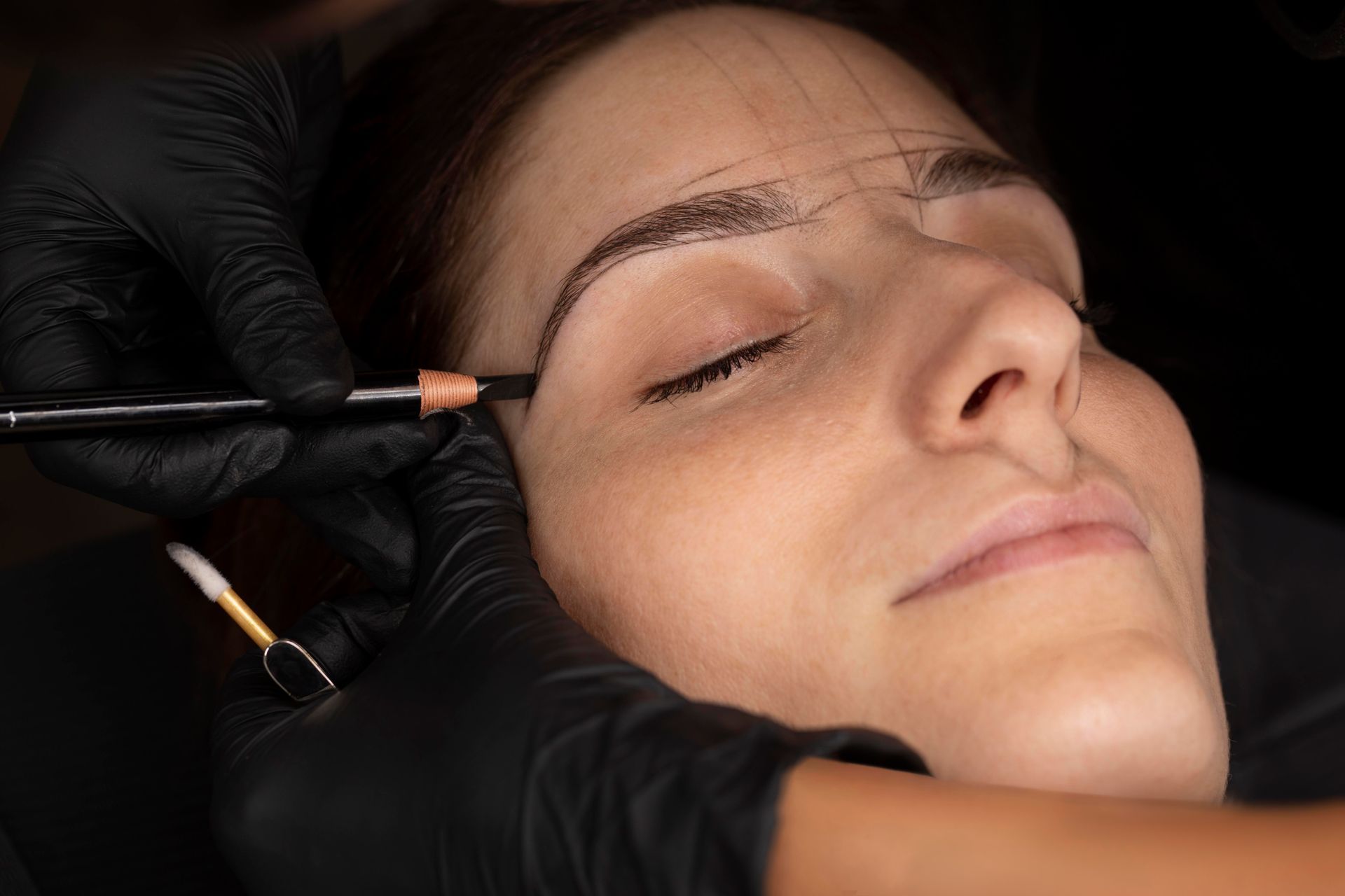 a woman is getting her eyebrows drawn by a makeup artist .