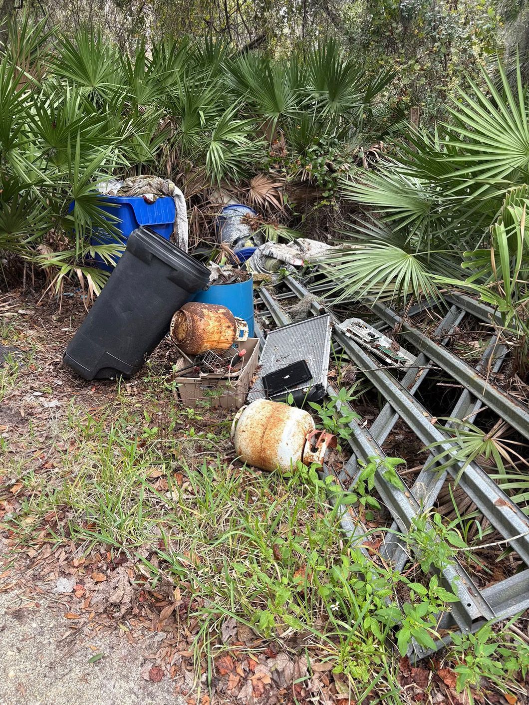 A pile of trash is sitting on the ground in the woods.
