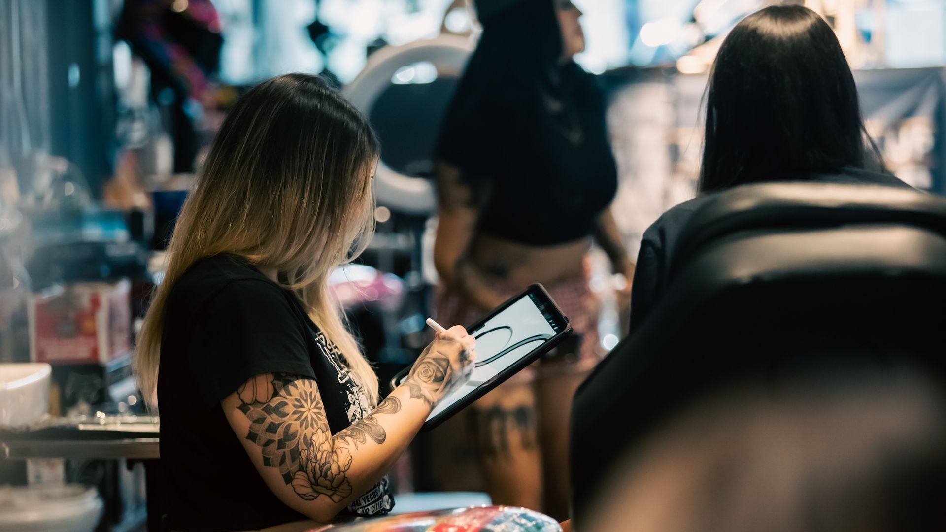 Tattoo artist sketching portrait design from reference images