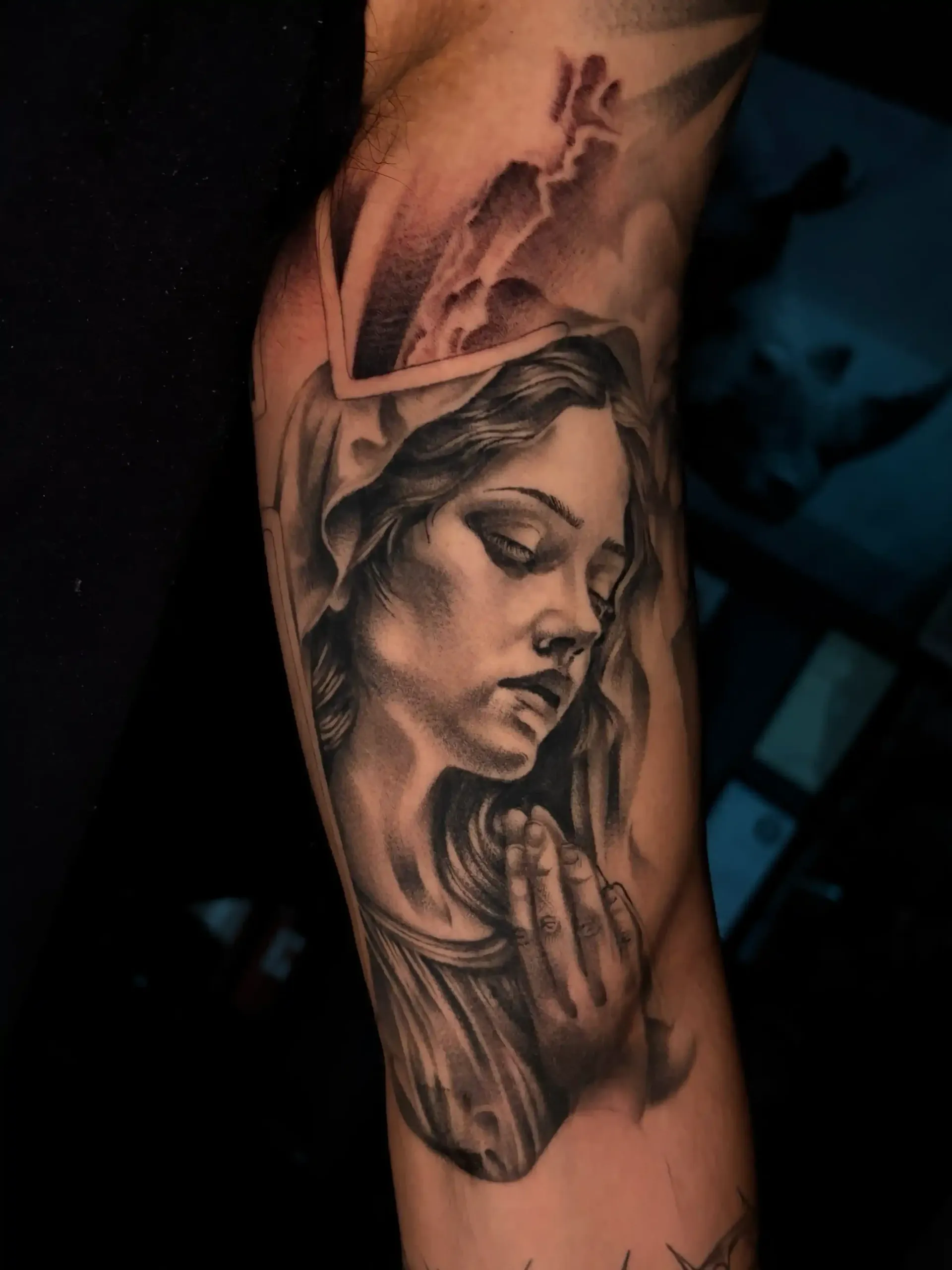 Black and grey religious tattoo of a praying figure by Savana Rodriguez at Black Rhino Tattoos in Las Vegas