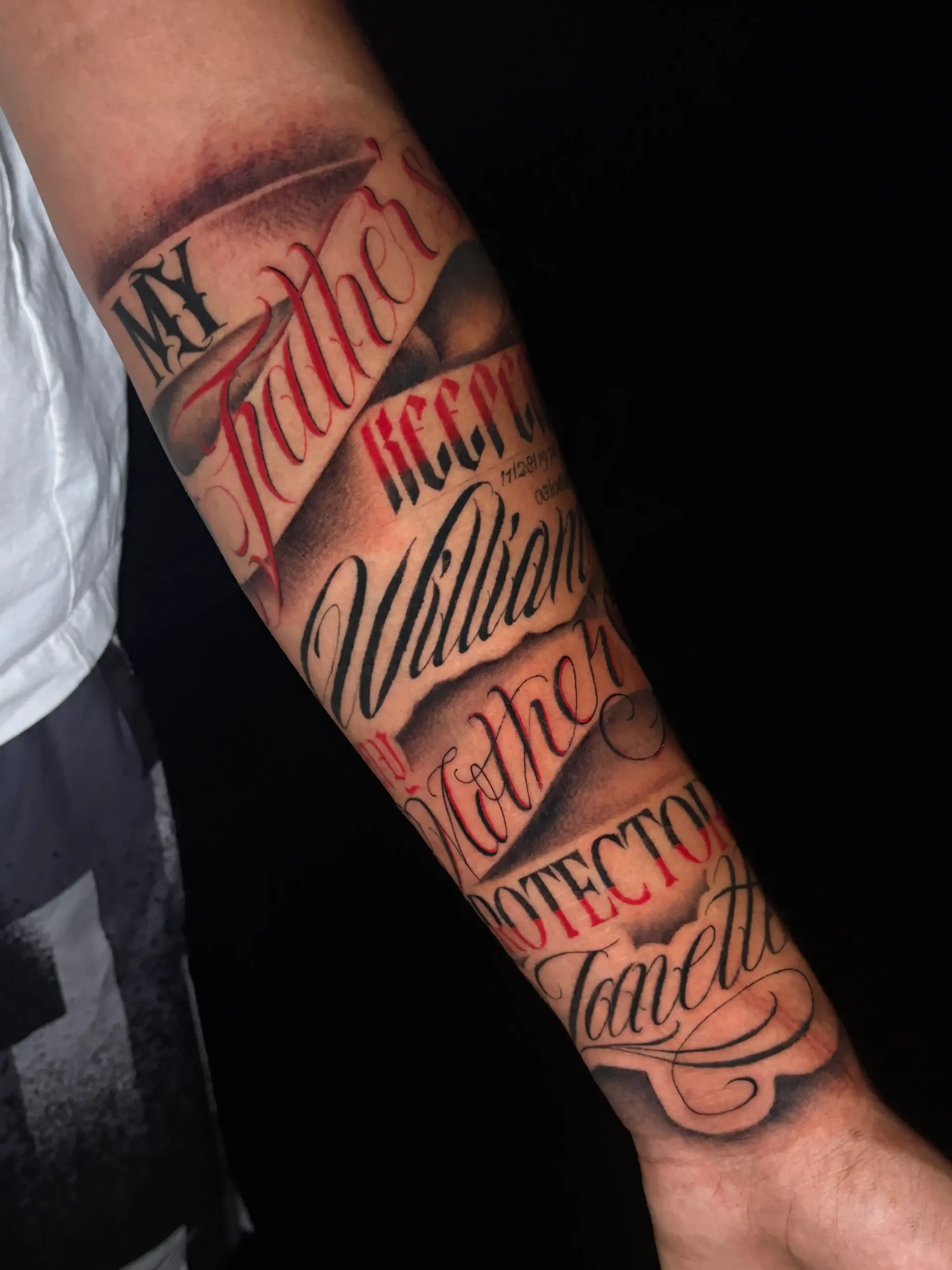 Black and red lettering tattoo on forearm by Savana Rodriguez at Black Rhino Tattoos in Las Vegas