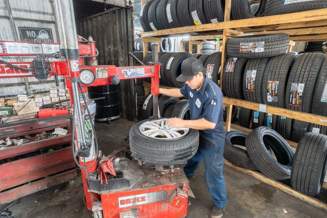 A mechanic changing a tire in a garage, using a tire changing machine.