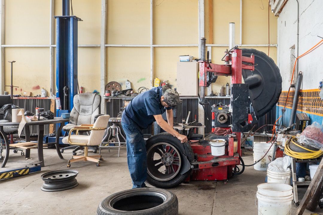 Mechanic changing a tire in a garage, using a tire-changing machine.