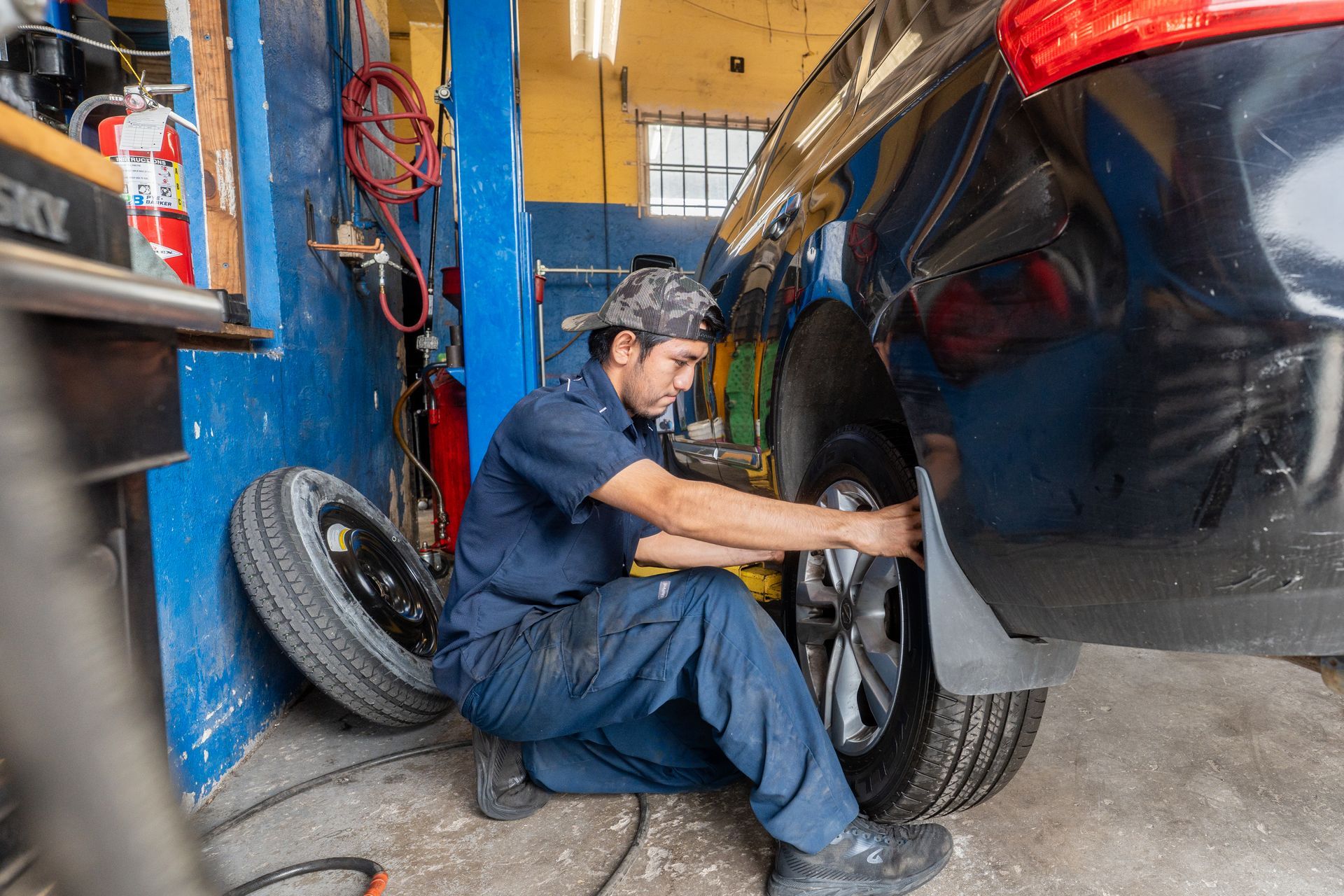 Mechanic using a pneumatic wrench to remove a car's wheel.