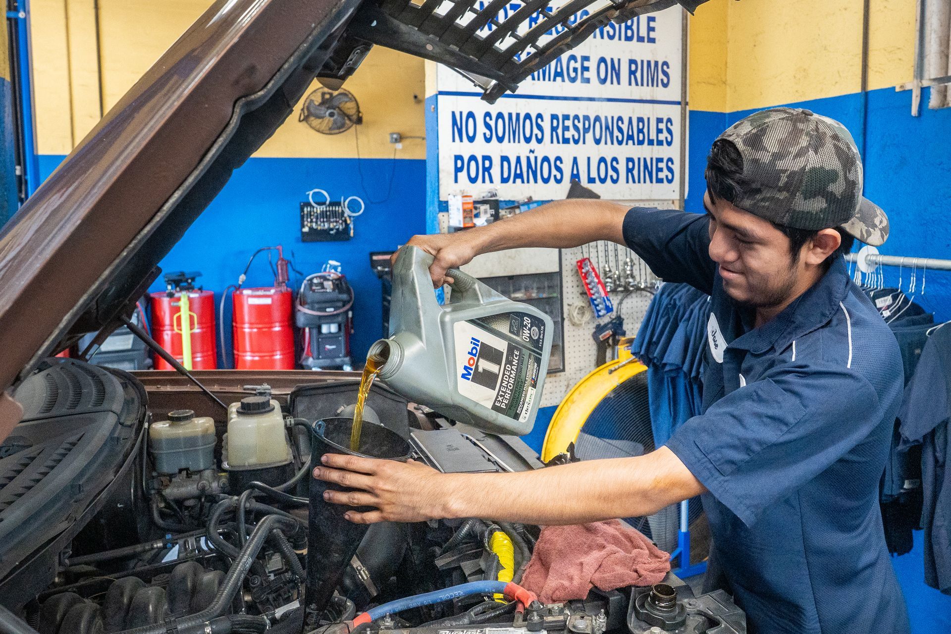 Person checking car oil level with dipstick. Engine bay is open.