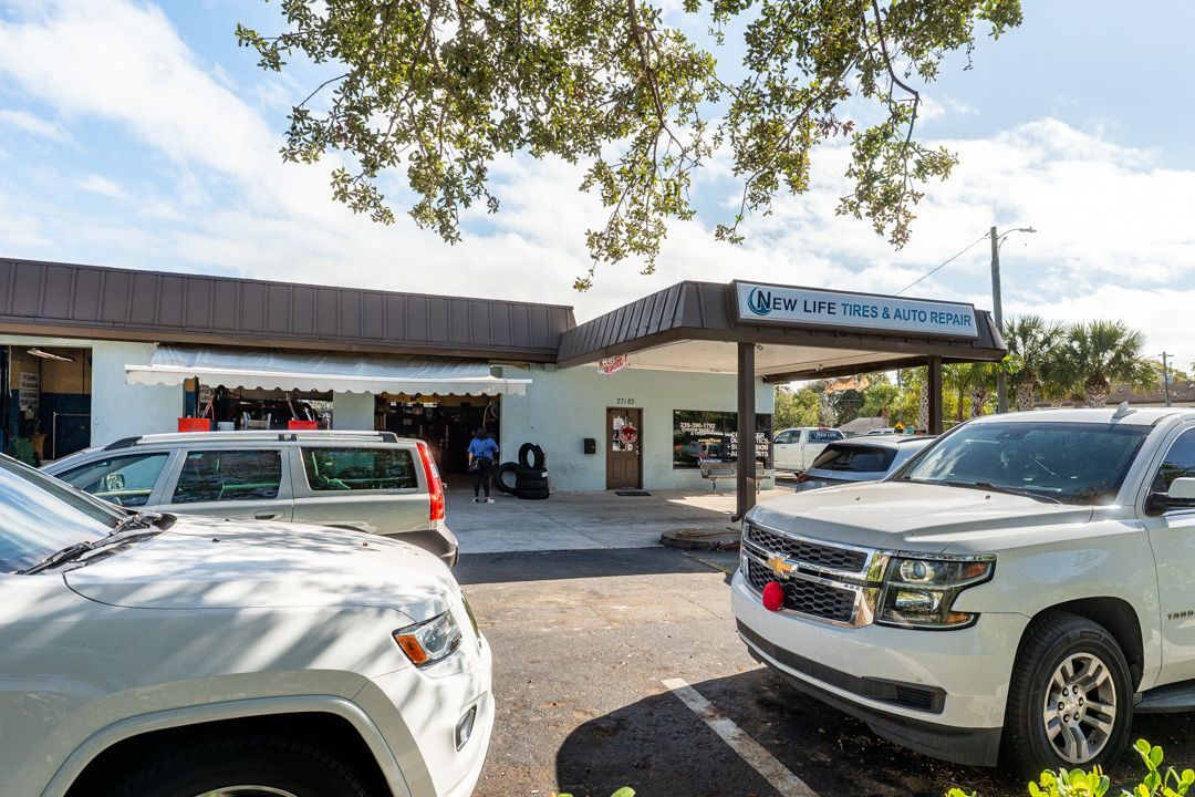 Cars parked outside a tire shop under a blue sky.