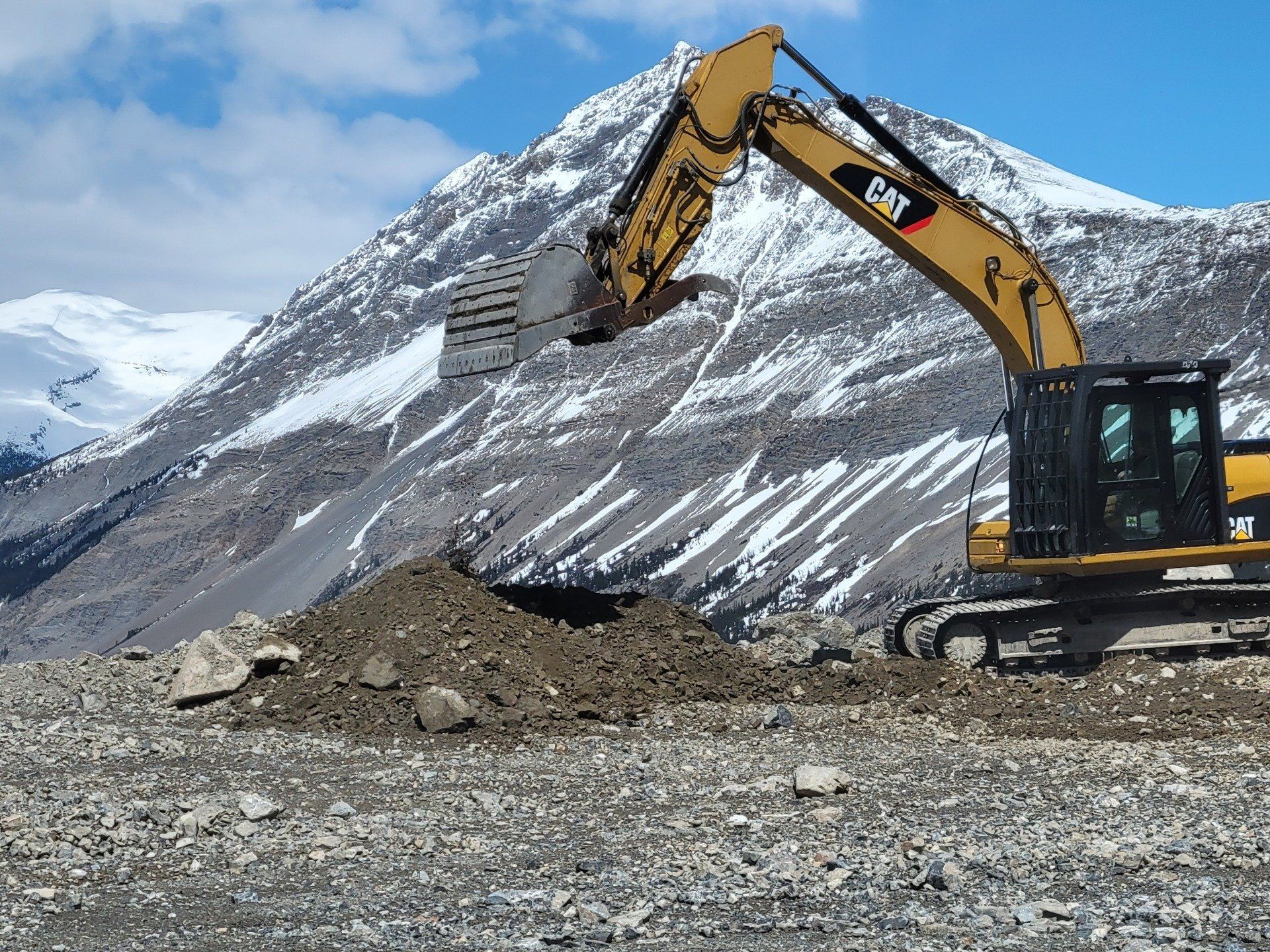 An excavator clearing unwanted earth off the side of a hill
