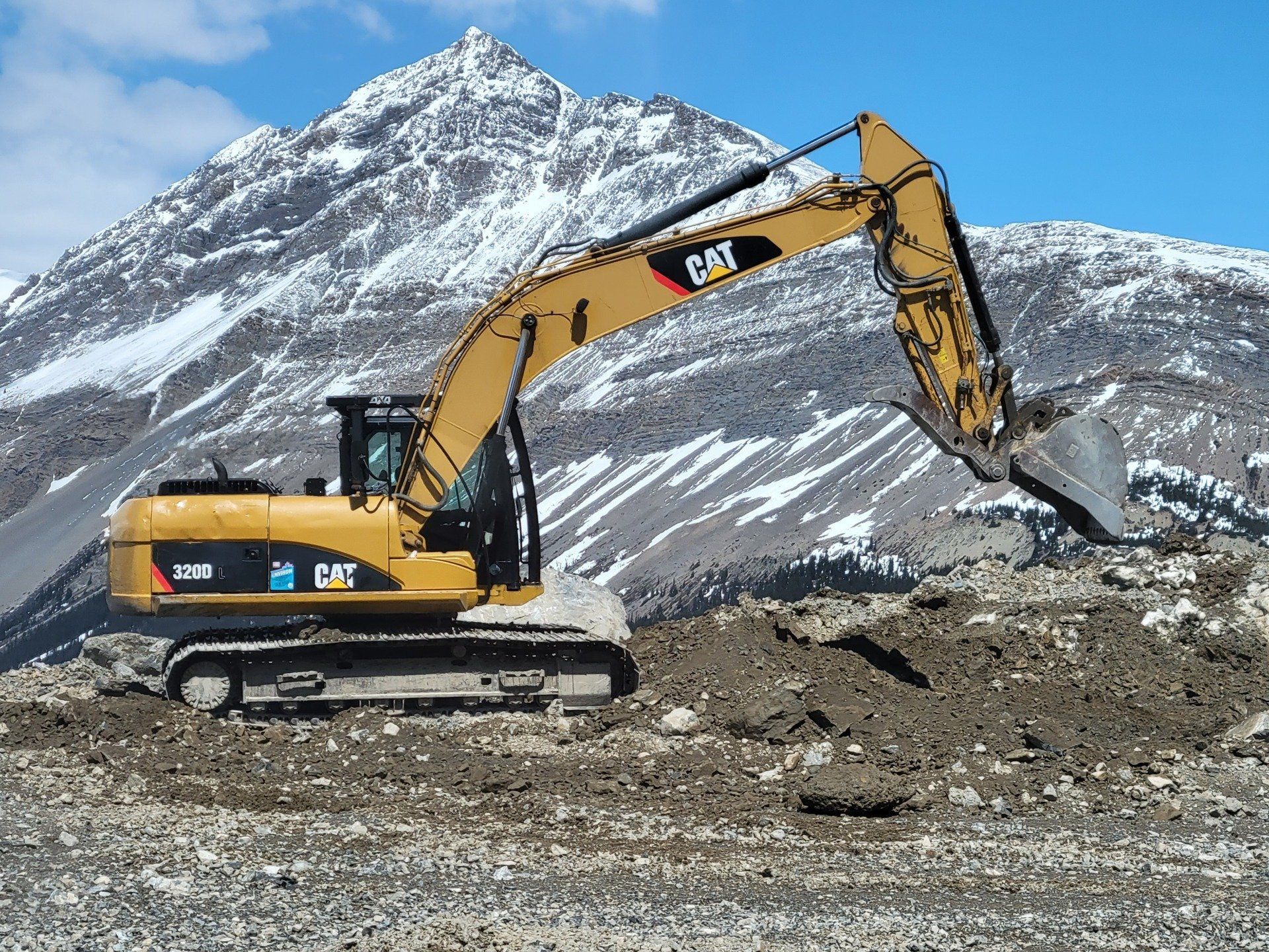 An excavator extending it's bucket to scoop up earth to remove it.