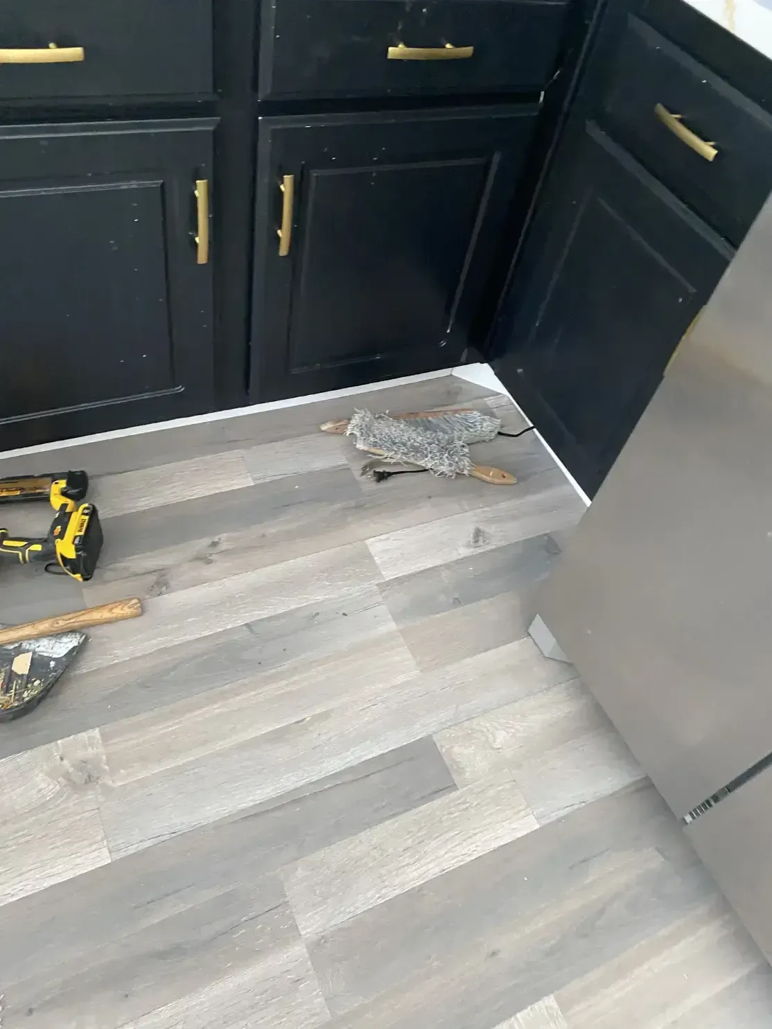 A kitchen floor with a drill and stapler on it.