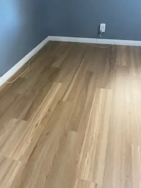 A room with a wooden floor and a gray wall.