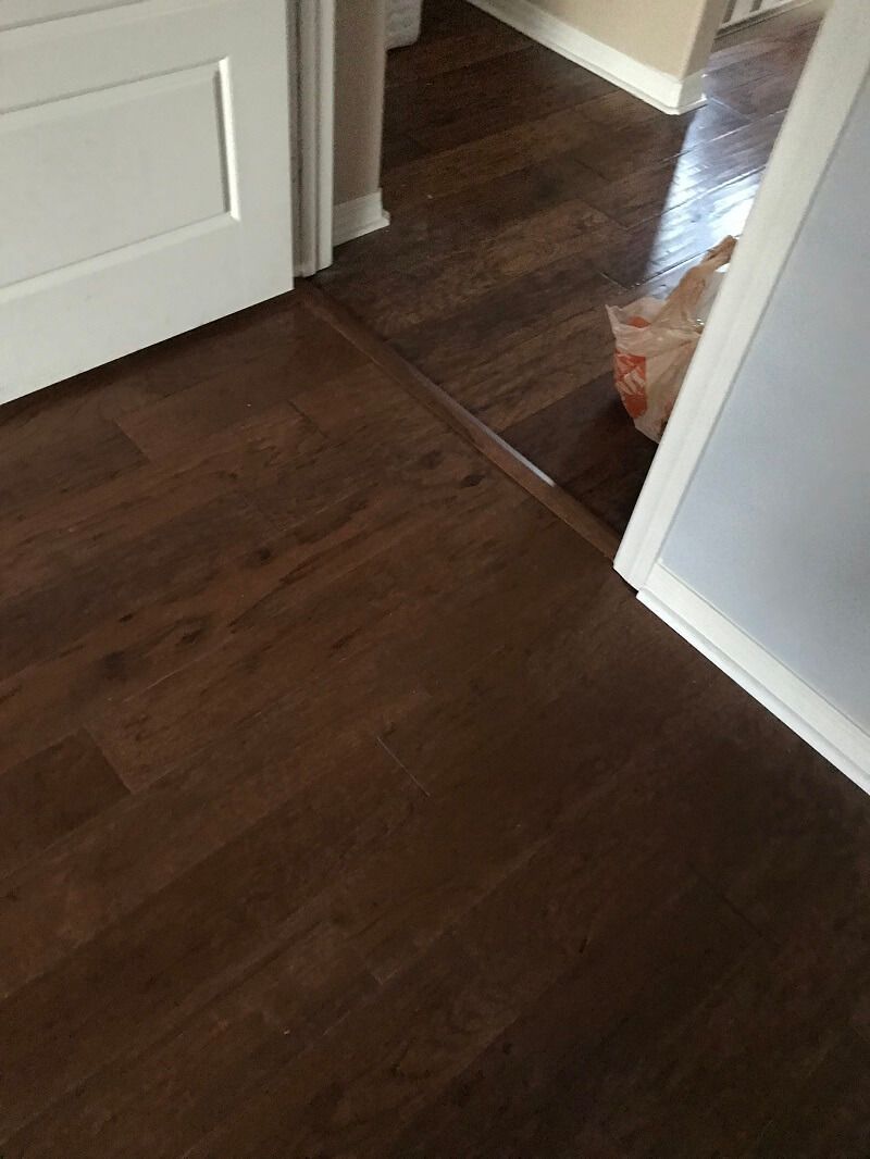 A wooden floor in a room next to a door.