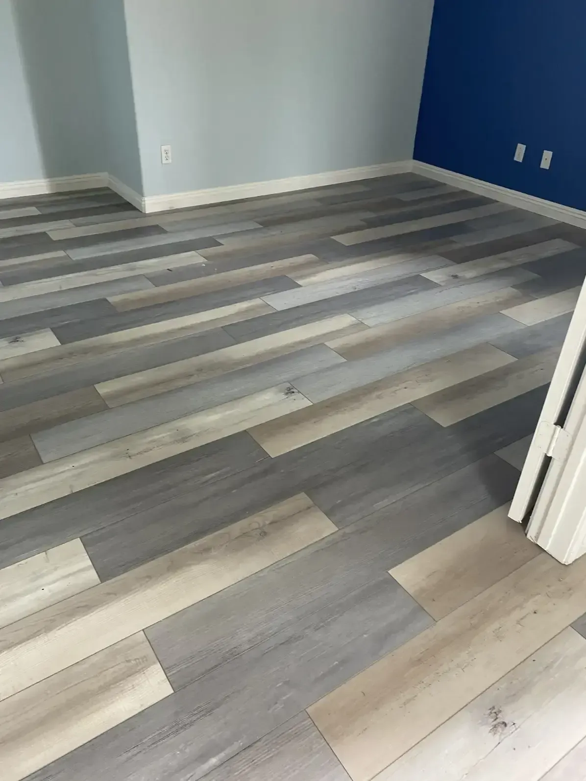 A room with a wooden floor and a blue wall.