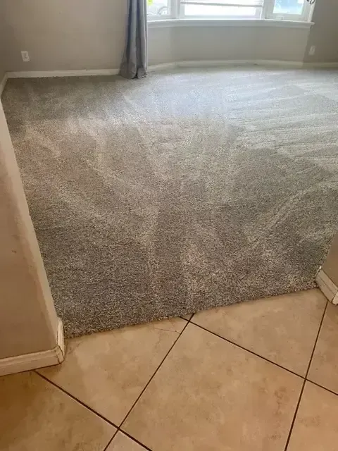 A living room with a gray carpet and tile floor.
