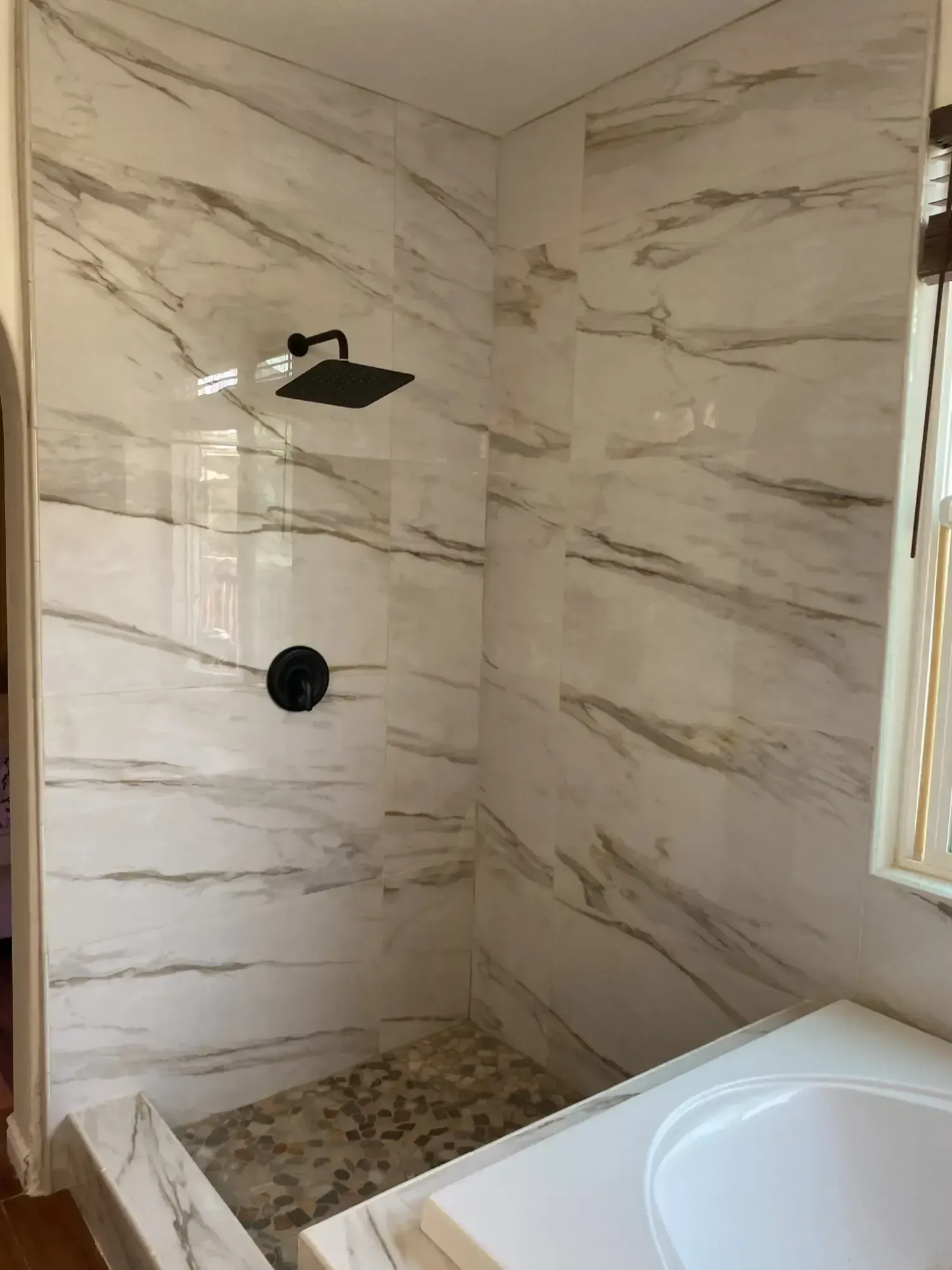 A bathroom with a walk in shower and a sink.