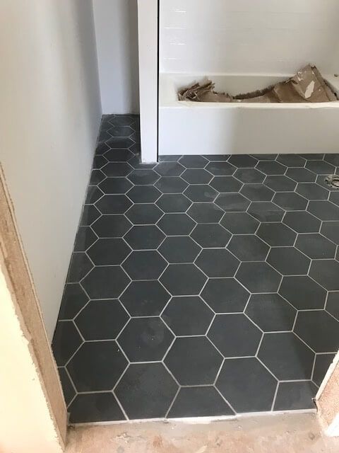 A bathroom with a hexagonal tile floor and a bathtub.