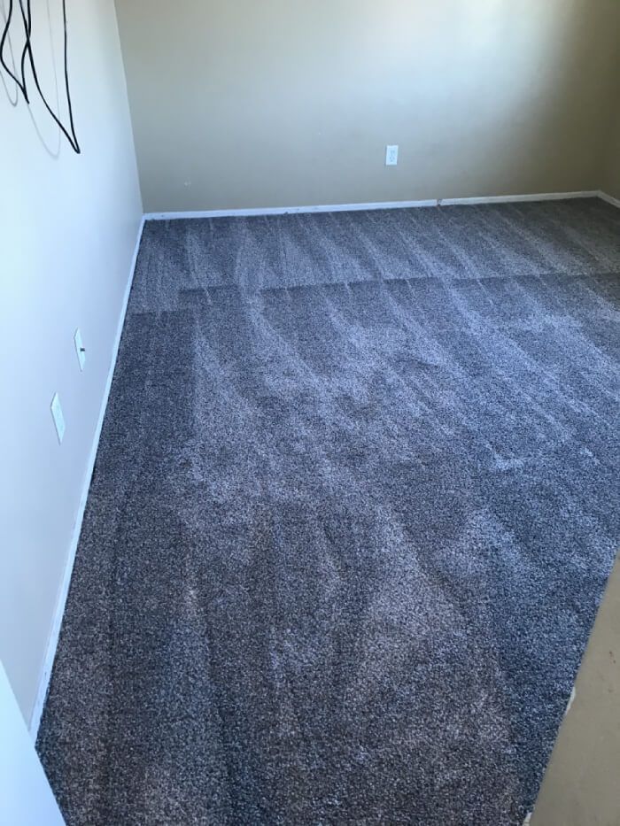 A bedroom with a carpeted floor and beige walls.