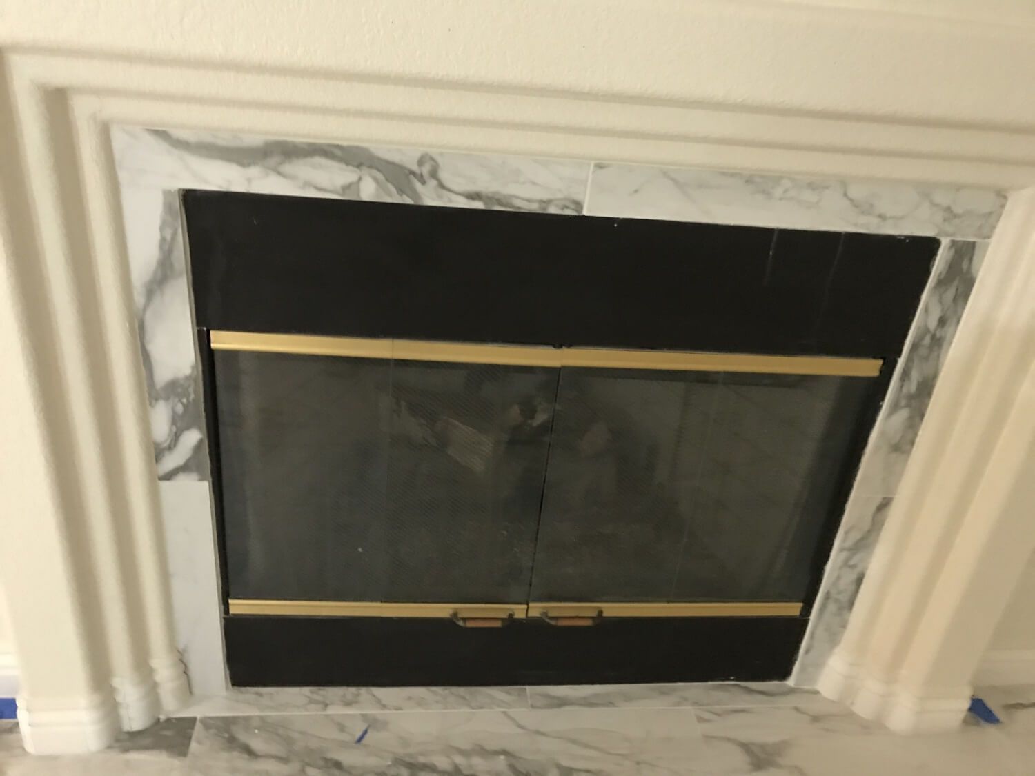 A fireplace with a black screen and gold trim