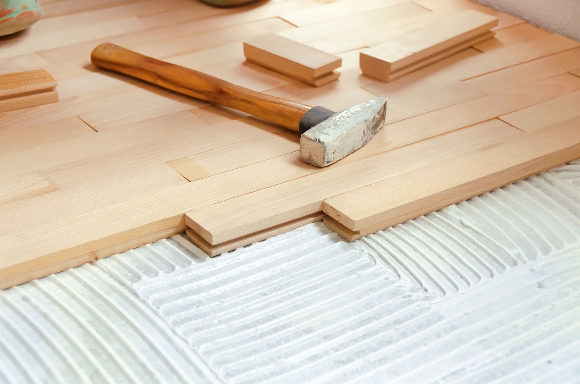 A hammer is sitting on top of a wooden floor.