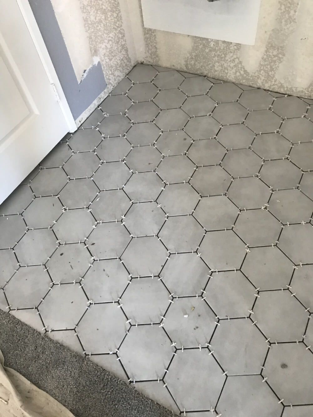A hexagon tile floor in a room with a door.